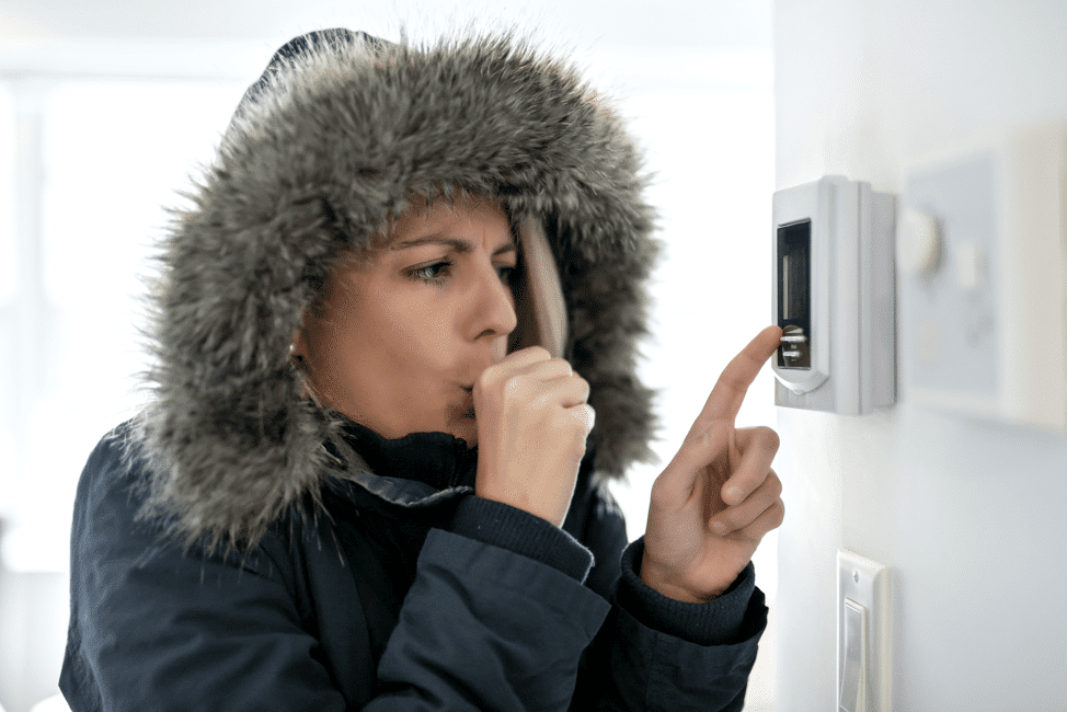 Cold woman using the thermostat